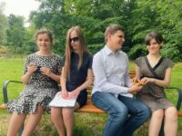 Zarząd siedzi na ławce w parku. Julita pisze coś na telefonie, Monika czyta brajlowski tekst na kartce papieru, Dawid pokazuje Mai jeden z wydruków.