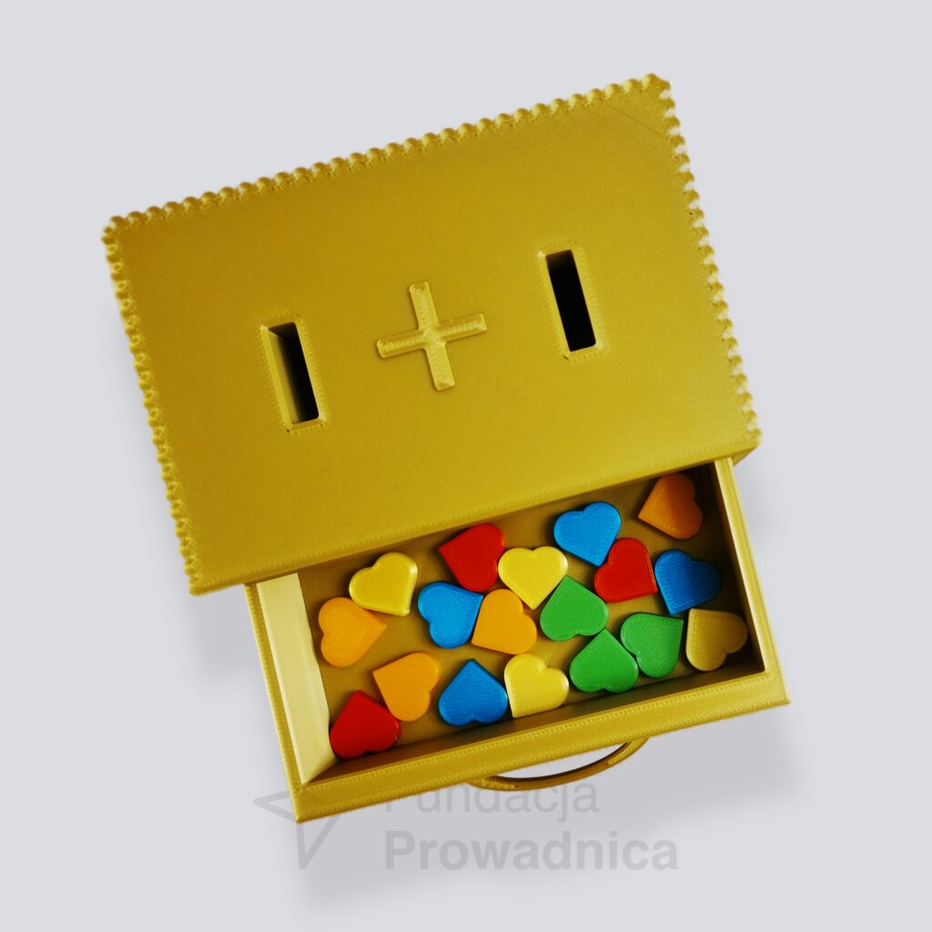 Dodawajka to niewielka skrzyneczka z dwoma otworami na górnej ściance i szufladką nieco niżej. W otwory wrzuca się serduszka, które następnie lądują w szufladce.