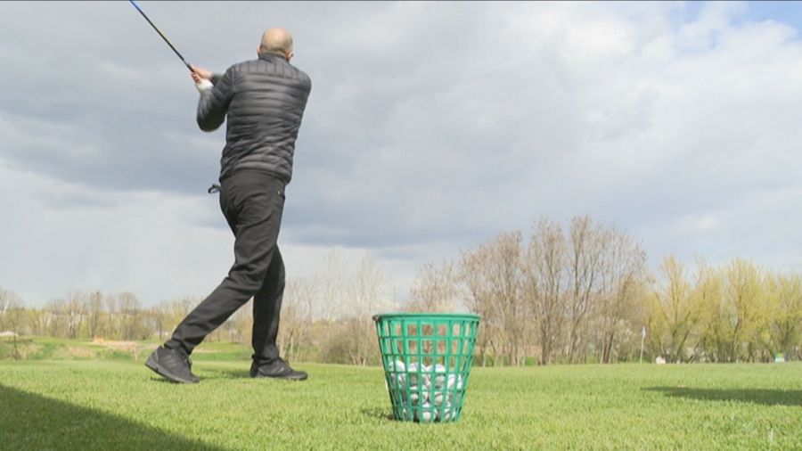 Grzegorz Kłak na polu z kijem golfowym.