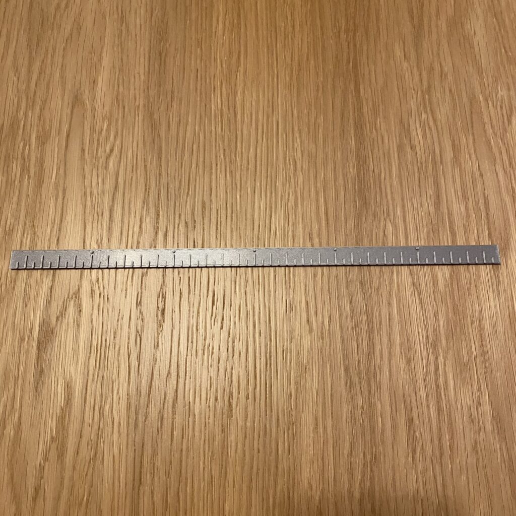 Srebrna linijka o długości 30 centymetrów i przedziałce pół centymetra.